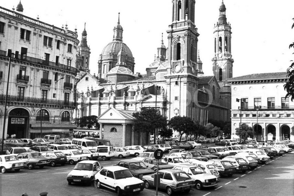 En esta atípica foto de la plaza del Pilar con coches aparcados de finales de los ochenta, podemos ver también el templete de la oficina municpal de turismo