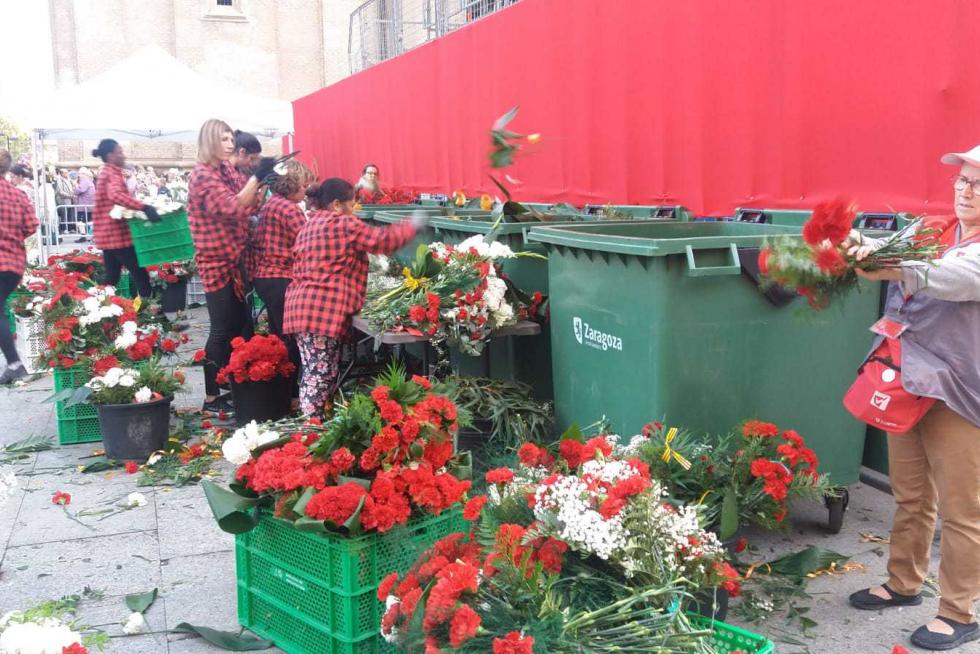 A espaldas de la Virgen decenas de voluntarios se afanan en preparar las flores para colocarlas en el manto.