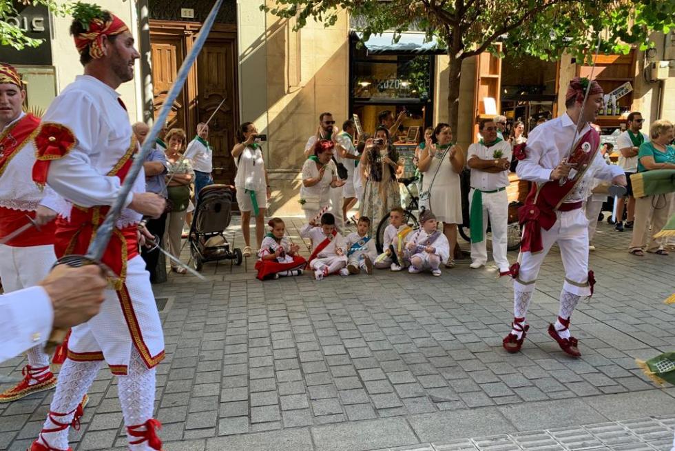 Vocación de danzante: unos niños vestidos como los miembros de la agrupación los jalean con los palos a su paso por el Coso.