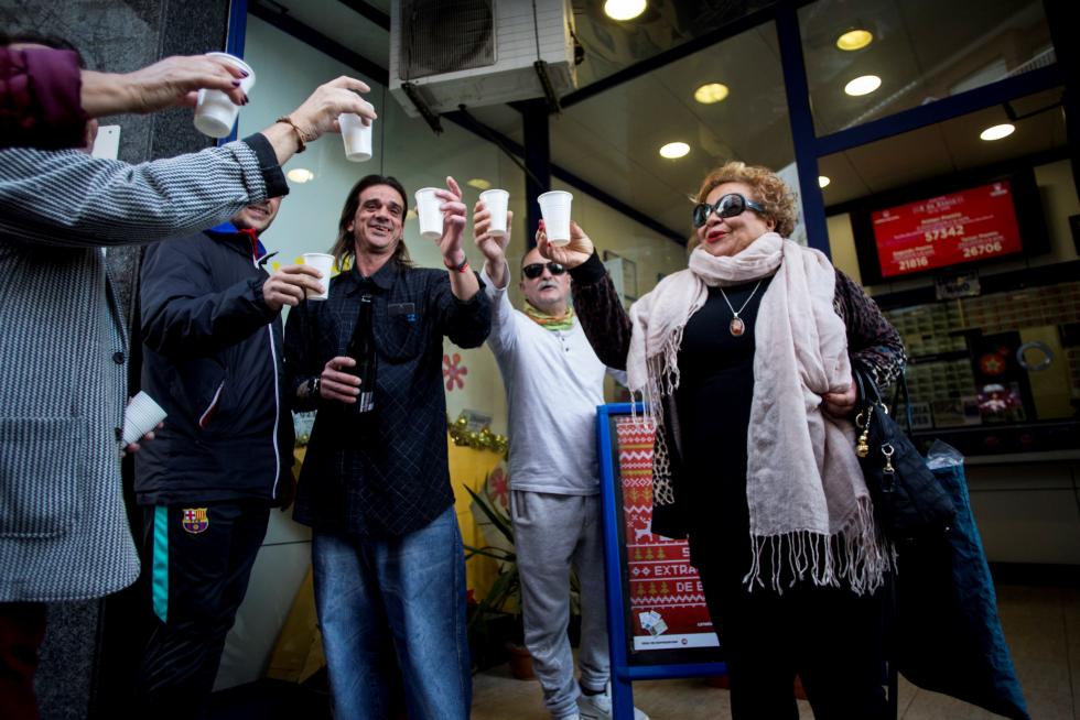El propietario de la administración de lotería número 2 de Pineda de Mar, Tarek Mathbout (c), celebra con vecinos del barrio que ha vendido parte del primer premio