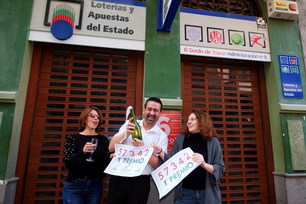 La administradora Ethel Mara Van Oudenhove Calero (d), su compañera en la administración Beatriz Memes Rodríguez (i) y un amigo de ambas, celebran haber repartido un décimo del primer premio