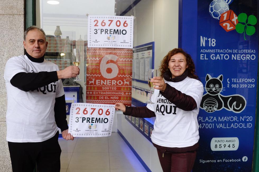 Los propietarios de la administración de lotería número 18 de Valladolid 'El gato negro', muestran el número con el tercer premio