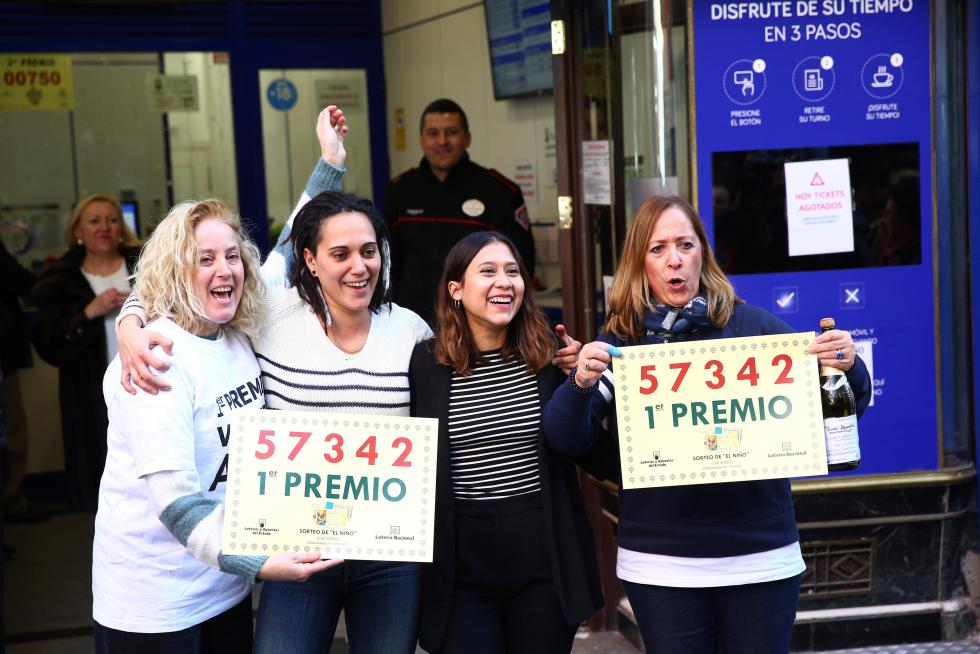 Un grupo de personas celebra en la administración de Lotería Doña Manolita haber dado parte del primer premio del sorteo del Niño