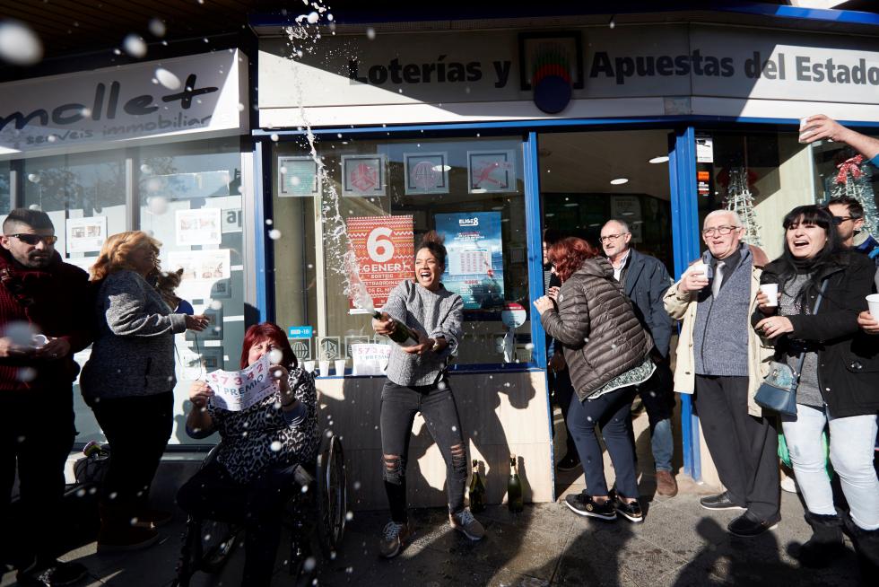 Varias personas festejan el primer premio del Sorteo extraordinario de El Niño, en la puerta de la administración de lotería de Mollet del Vallés