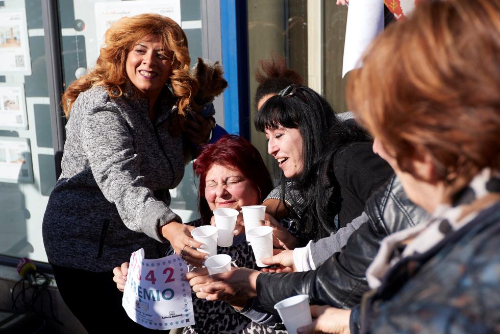 Varias personas festejan el primer premio del Sorteo extraordinario de El Niño, en la puerta de la administración de lotería de Mollet del Vallés