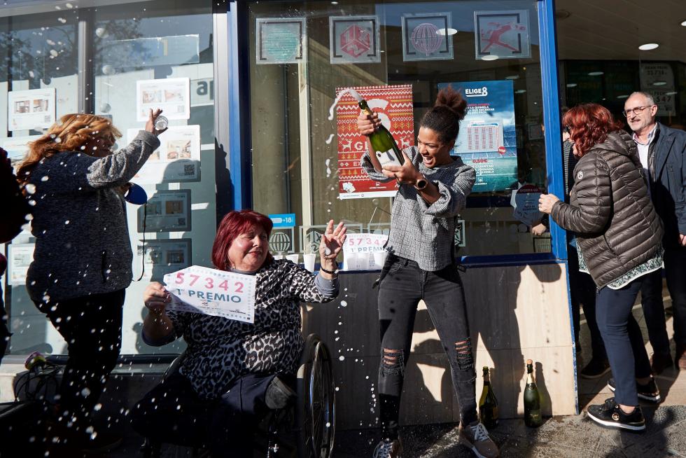 Varias personas festejan el primer premio del Sorteo extraordinario de El Niño, en la puerta de la administración de lotería de Mollet del Vallés