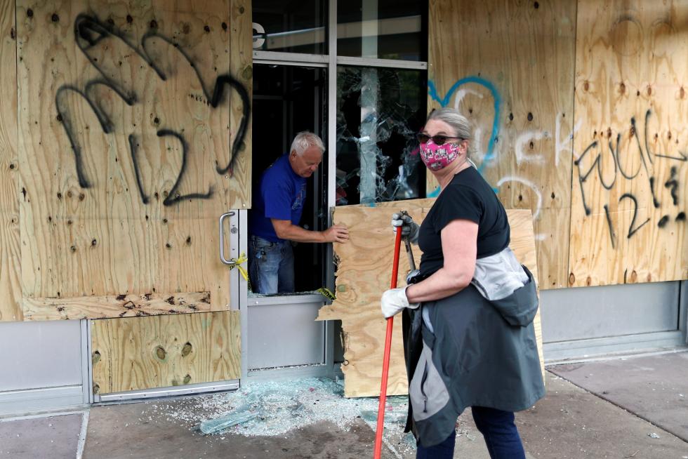 People clean up outside a local business in the area in the aftermath of a protest, in Minneapolis