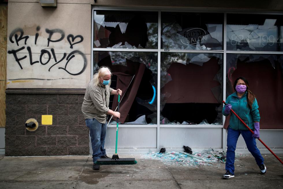 People clean up outside a local business in the area in the aftermath of a protest, in Minneapolis