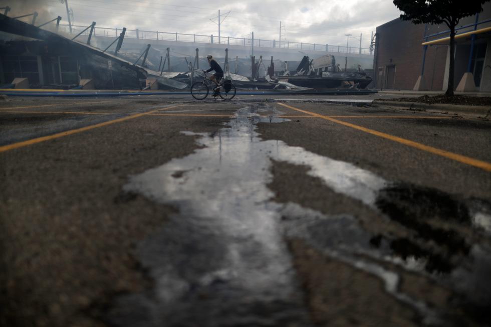 Person rides a bicycle at the area in the aftermath of a protest, in Minneapolis