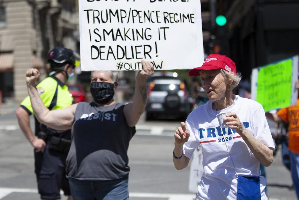 Boston (United States), 30/05/2020.- A protester affixes a 'Straight Pride' flag to a 'Trump 2020' flag in front of the Massachusetts Statehouse, while calling for the Governor to reopen the Commonwealth in Boston, Massachusetts, USA, 30 May 2020. Massachusetts Governor has introduced a four phase plan to reopen the state in an effort to control the spread of the COVID-19 coronavirus disease. (Protestas, Abierto, Estados Unidos) EFE/EPA/CJ GUNTHER Protest for and against the reopneing the Commonwealth of Massachusetts