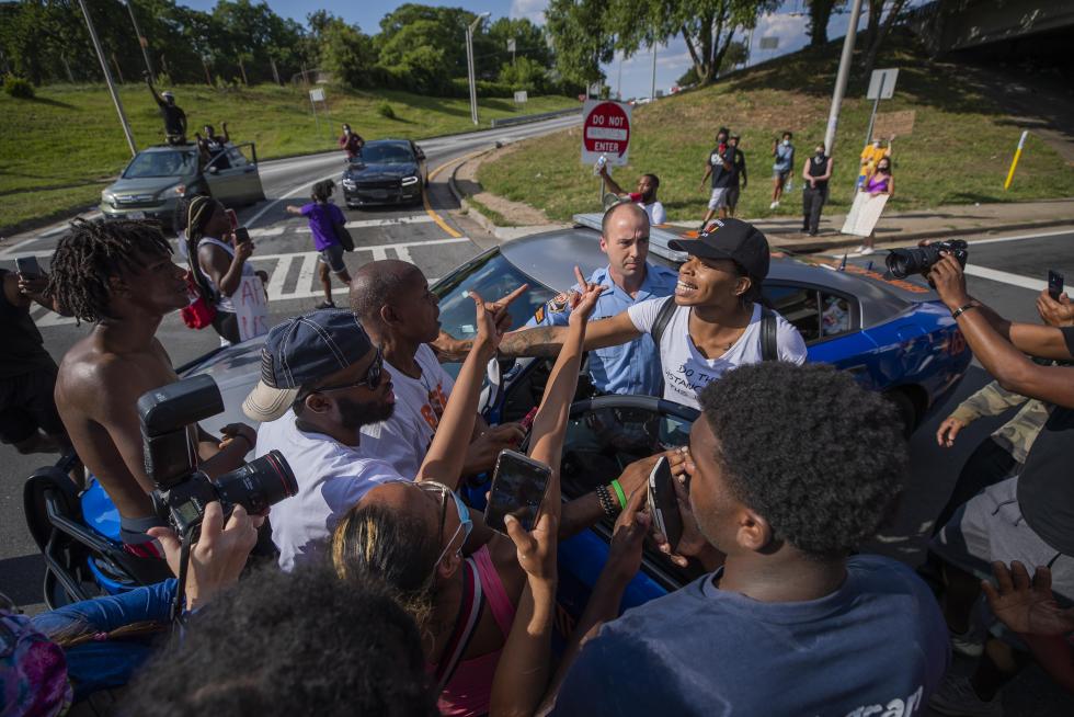 Atlanta (United States), 13/06/2020.- Georgia State Patrol Trooper Corporal S. Stone is surrounded by angry protesters near the scene of an overnight Atlanta Police Department officer involved shooting which left a black man dead at a Wendy's restaurant in Atlanta, Georgia, USA, 13 June 2020. Atlanta Police Chief Erika Shields has stepped down in the wake of the shooting. The Georgia Bureau of Investigation is looking into the shooting of Rayshard Brooks, 27, after a reported struggle with officers ensued during which a Taser was used late 12 June 2020. (Protestas, Estados Unidos) EFE/EPA/ERIK S. LESSER Black man shot and killed during incident with the Atlanta Police Department