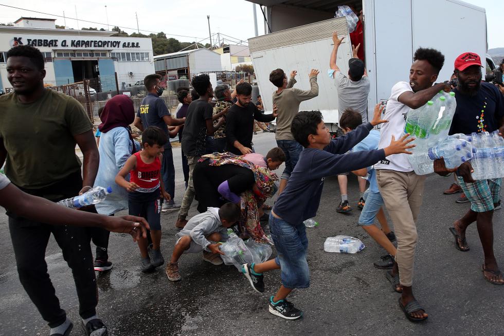 Kara Tepe (Greece), 12/09/2020.- Asylum seekers scuffle to get some water near the new camp at Kara Tepe on Lesbos island, Greece, 12 September 2020. Thousands of migrants and refugees are still without shelter following the successive fires at the Moria Reception and Identification Centre. A fire broke out in the overcrowded Moria Refugee Camp early 09 September 2020, destroying large parts of some 13,000 refugees' accommodations. The military camp which serves as a European Union's so-called 'hotspot' was designed to hold some 3,000 people, but has at times been the dwelling of some 20,000 refugees. (Incendio, Grecia, Estados Unidos) EFE/EPA/ORESTIS PANAGIOTOU Asylum seekers at the new camp at Kara Tepe