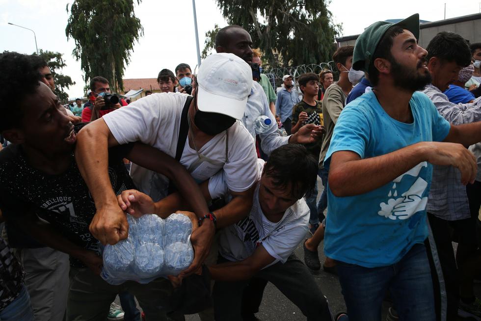 Kara Tepe (Greece), 12/09/2020.- Asylum seekers scuffle to get some water near the new camp at Kara Tepe on Lesbos island, Greece, 12 September 2020. Thousands of migrants and refugees are still without shelter following the successive fires at the Moria Reception and Identification Centre. A fire broke out in the overcrowded Moria Refugee Camp early 09 September 2020, destroying large parts of some 13,000 refugees' accommodations. The military camp which serves as a European Union's so-called 'hotspot' was designed to hold some 3,000 people, but has at times been the dwelling of some 20,000 refugees. (Incendio, Grecia, Estados Unidos) EFE/EPA/ORESTIS PANAGIOTOU Asylum seekers at the new camp at Kara Tepe