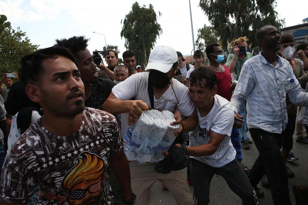 Kara Tepe (Greece), 12/09/2020.- Asylum seekers scuffle to get some water near the new camp at Kara Tepe on Lesbos island, Greece, 12 September 2020. Thousands of migrants and refugees are still without shelter following the successive fires at the Moria Reception and Identification Centre. A fire broke out in the overcrowded Moria Refugee Camp early 09 September 2020, destroying large parts of some 13,000 refugees' accommodations. The military camp which serves as a European Union's so-called 'hotspot' was designed to hold some 3,000 people, but has at times been the dwelling of some 20,000 refugees. (Incendio, Grecia, Estados Unidos) EFE/EPA/ORESTIS PANAGIOTOU Asylum seekers at the new camp at Kara Tepe