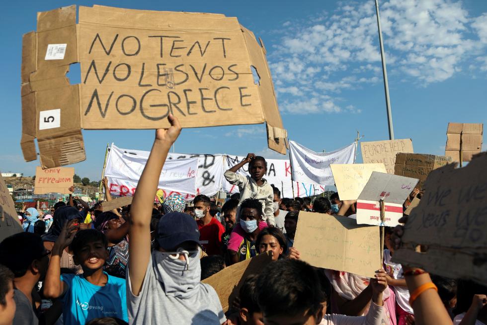 Moria (Greece), 12/09/2020.- Asylum seekers protest against the new camp at Kara Tepe on Lesbos island, Greece, 12 September 2020. Migrants and refugees oppose plans to be hosted in a new camp and ask to travel to their destinations. Thousands of migrants and refugees are still without shelter following the successive fires at the Moria Reception and Identification Centre. A fire broke out in the overcrowded Moria Refugee Camp early 09 September 2020, destroying large parts of some 13,000 refugees' accommodations. The military camp which serves as a European Union's so-called 'hotspot' was designed to hold some 3,000 people, but has at times been the dwelling of some 20,000 refugees. (Protestas, Incendio, Grecia, Estados Unidos) EFE/EPA/ORESTIS PANAGIOTOU Protests against the new camp at Kara Tepe