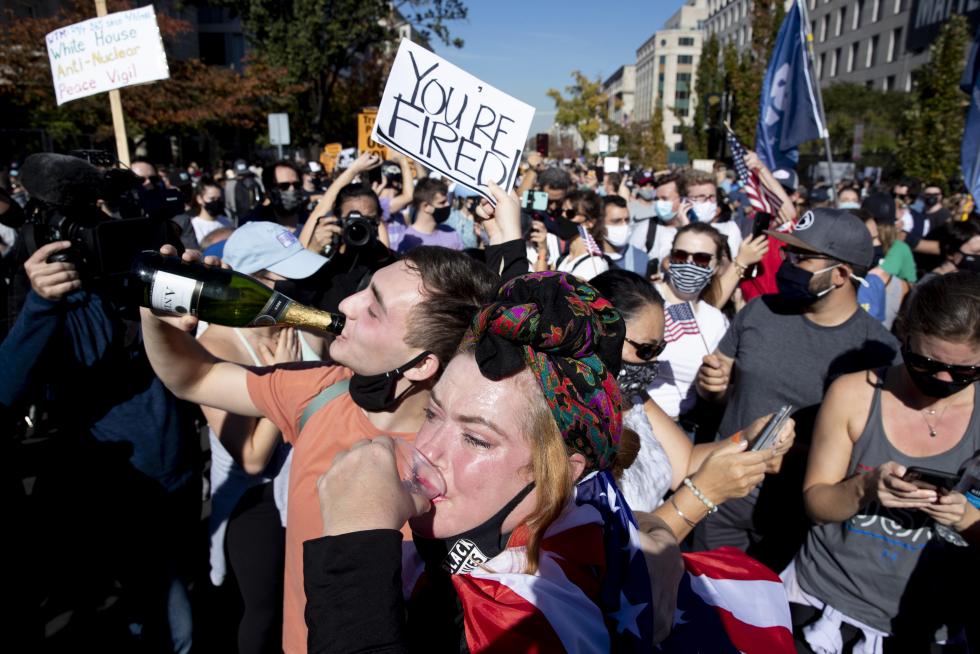 Washington (United States), 07/11/2020.- A woman drinks champagne and holds a sign that says 'You're Fired' as people celebrate after news organizations called the US 2020 presidential election for Joe Biden, defeating incumbent US President Donald J. Trump, on Black Lives Matter near the White House in Washington, DC, USA, 07 November 2020. (Incendio, Estados Unidos) EFE/EPA/MICHAEL REYNOLDS Election 2020 reactions in Washington, DC
