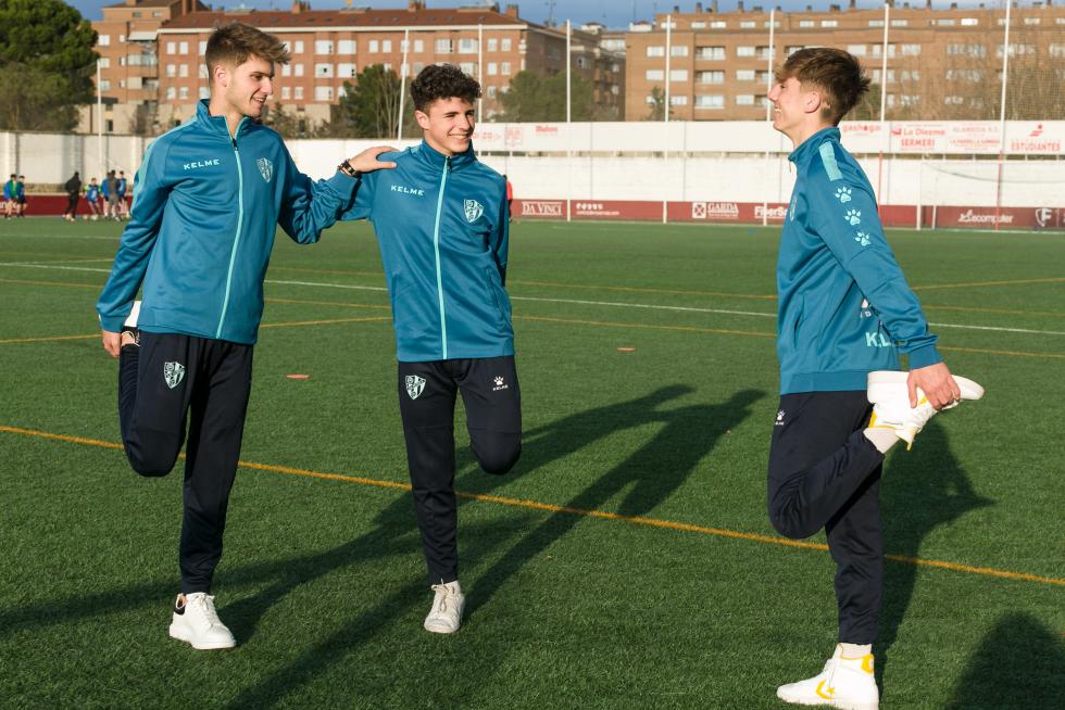 Los futbolistas de las categorías inferiores de la SD Huesca estiran tras la sesión.