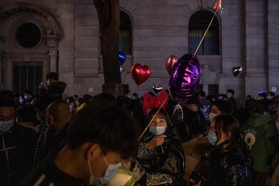 Wuhan (China), 31/12/2020.- People with and without protective masks on their faces walk in a street on New Year's Eve in Wuhan, China, 31 December 2020. Life in Wuhan, a Chinese city of more than 11 million, which nearly a year ago became the epicenter of the coronavirus outbreak is returning to normal. EFE/EPA/ROMAN PILIPEY New Year in Wuhan