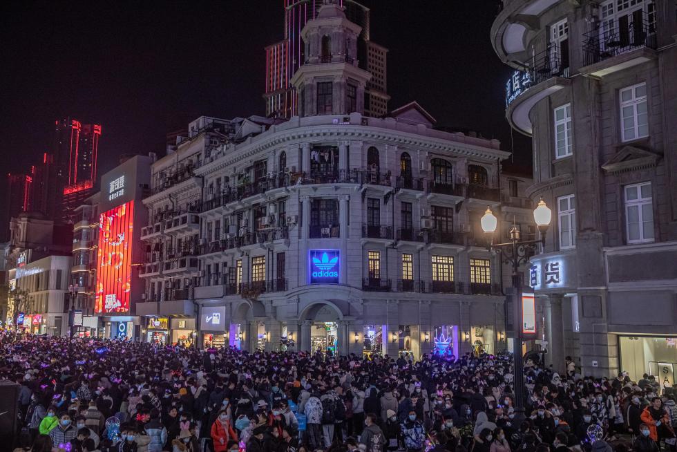 Wuhan (China), 31/12/2020.- People with and without protective masks on their faces walk in a street on New Year's Eve in Wuhan, China, 31 December 2020. Life in Wuhan, a Chinese city of more than 11 million, which nearly a year ago became the epicenter of the coronavirus outbreak is returning to normal. EFE/EPA/ROMAN PILIPEY New Year in Wuhan