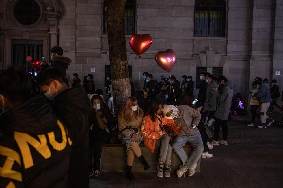 Wuhan (China), 31/12/2020.- People with and without protective masks on their faces walk in a street on New Year's Eve in Wuhan, China, 31 December 2020. Life in Wuhan, a Chinese city of more than 11 million, which nearly a year ago became the epicenter of the coronavirus outbreak is returning to normal. EFE/EPA/ROMAN PILIPEY New Year in Wuhan