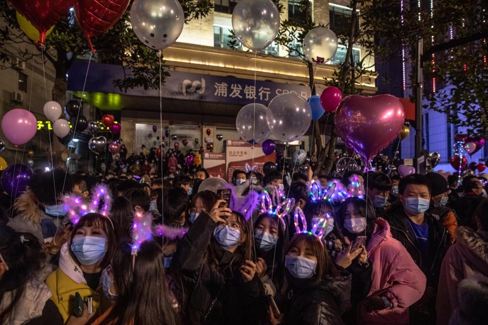 Wuhan (China), 31/12/2020.- A couple wearing protective face masks pose for photos in a street on New Year's Eve in Wuhan, China, 31 December 2020. Life in Wuhan, a Chinese city of more than 11 million, which nearly a year ago became the epicenter of the coronavirus outbreak is returning to normal. EFE/EPA/ROMAN PILIPEY New Year in Wuhan