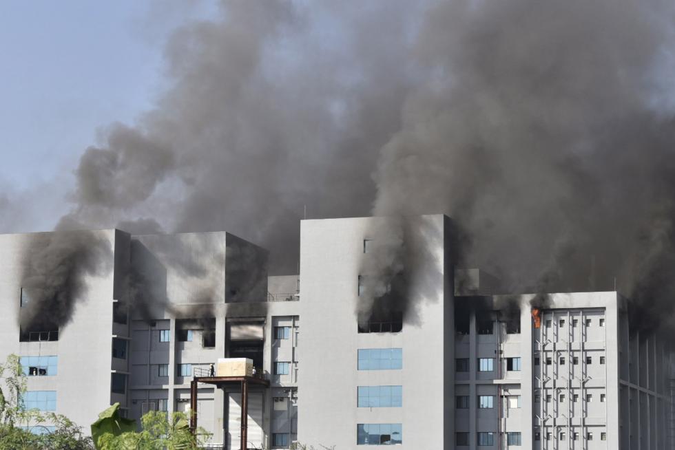 Pune (India), 21/01/2021.- Indian workers stand near smoke rising from a building of the Covid vaccine-maker Serum Institute of India's Pune facility after a fire broke out in Pune Maharashtra, India, 21 January 2021. A massive fire broke out in one of an under construction building of the facility which is spread over 100 acres and no damage and causality reported as many fire engines reached the spot. (Cine, Incendio, Estados Unidos) EFE/EPA/STR Fire at the Serum Institute of India's Pune facility in India