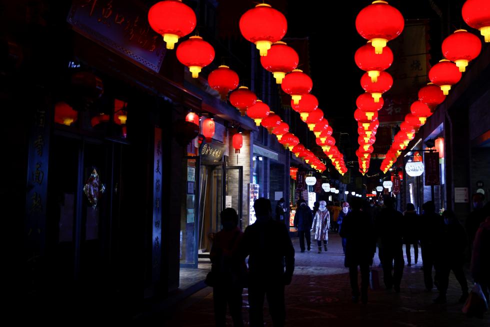 FILE PHOTO: People wearing face masks following an outbreak of the coronavirus disease (COVID-19) walk near the Qianmen street ahead of Lunar New Year celebrations, in Beijing