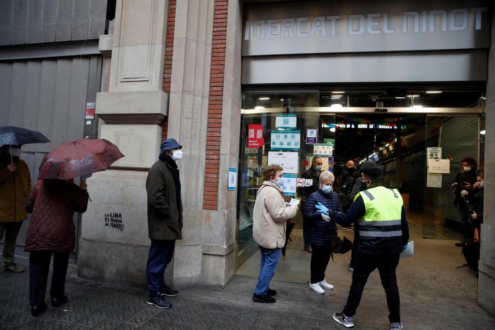 Varias personas hacen cola para votar en el colegio electoral situado en el Mercat del Ninot en Barcelona.