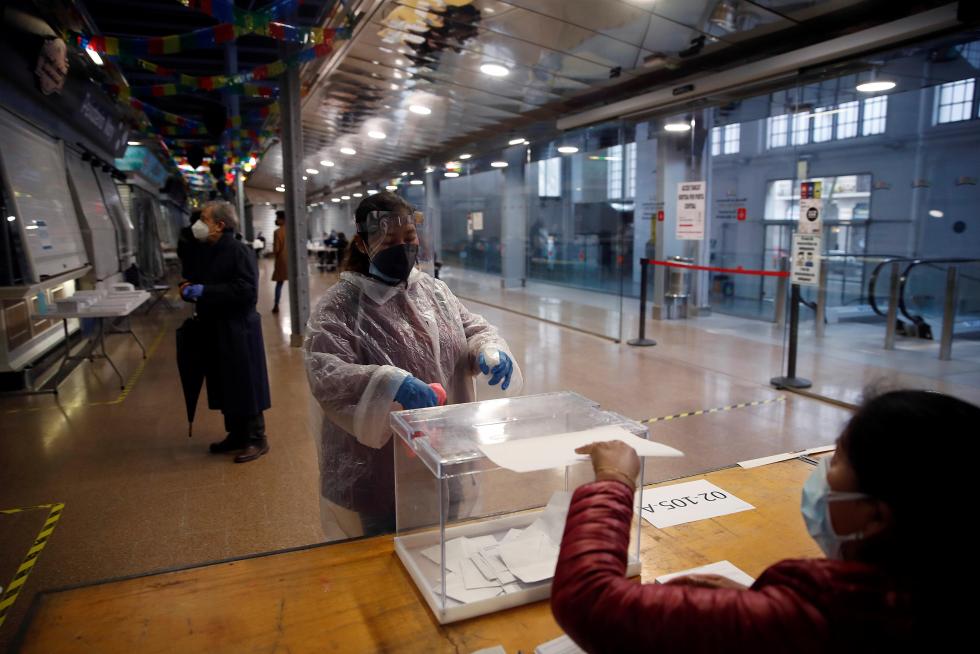 Una mujer protegida con un traje vota en el colegio electoral situado en el Mercat del Ninot en Barcelona.
