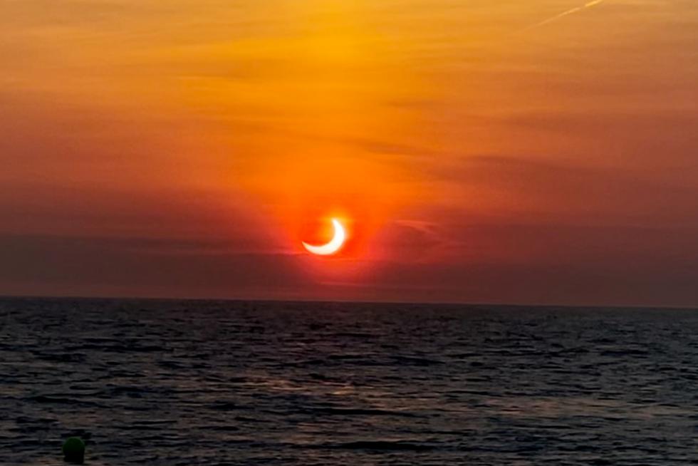 Partial solar eclipse is seen above the horizon in Avon-by-the-Sea