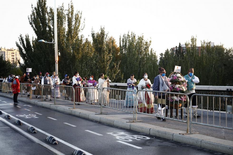 La Ofrenda va avanzando, el manto de la Virgen se está cubriendo ya y el color inunda la plaza. Al otro lado de las vallas, algunos curiosos intentan vislumbrar lo que ocurre.