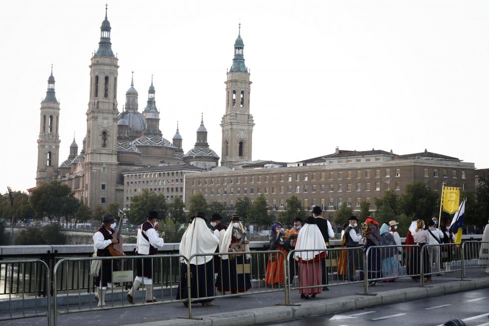 La Ofrenda va avanzando, el manto de la Virgen se está cubriendo ya y el color inunda la plaza. Al otro lado de las vallas, algunos curiosos intentan vislumbrar lo que ocurre.