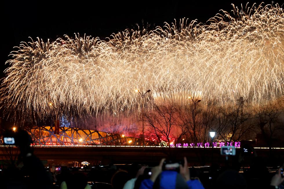 People watch from a parking lot as fireworks explode over the National Stadium, also known as the Bird's Nest, at the end of the closing ceremony of the Beijing 2022 Winter Olympics, in Beijing, China February 20, 2022. REUTERS/Carlos Garcia Rawlins OLYMPICS-2022-CLOSING/
