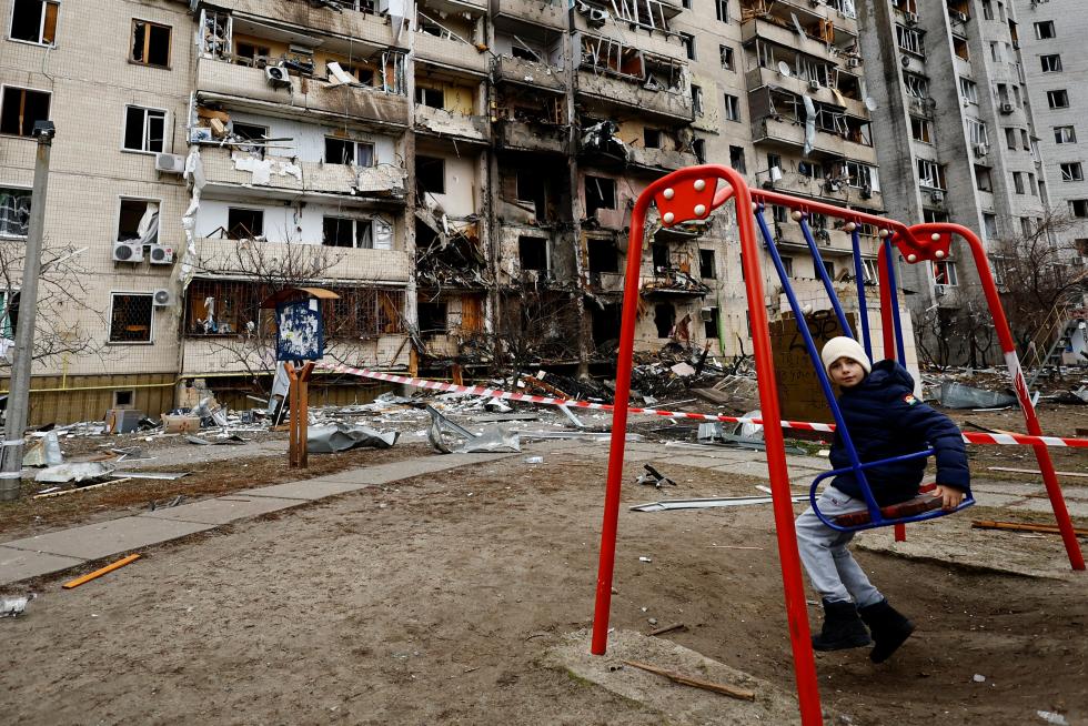 A person walks his dog in front of a damaged residential building, after Russia launched a massive military operation against Ukraine, in Kyiv, Ukraine February 25, 2022. REUTERS/Umit Bektas UKRAINE-CRISIS/