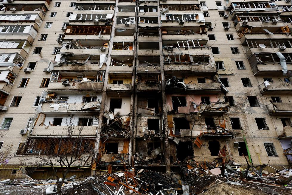 A child sits on a swing in front of a damaged residential building, after Russia launched a massive military operation against Ukraine, in Kyiv, Ukraine February 25, 2022. REUTERS/Umit Bektas UKRAINE-CRISIS/