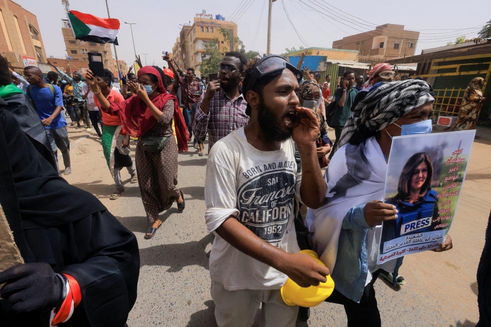Egyptian journalist Ibrahim El-Masry holds up his camera as he stands next to a placard with a picture of Al Jazeera reporter Shireen Abu Akleh, who was killed during an Israeli raid in Jenin, during a protest outside the Israeli consulate in Istanbul, Turkey May 12, 2022. REUTERS/Dilara Senkaya PALESTINIANS-ISRAEL/JOURNALIST