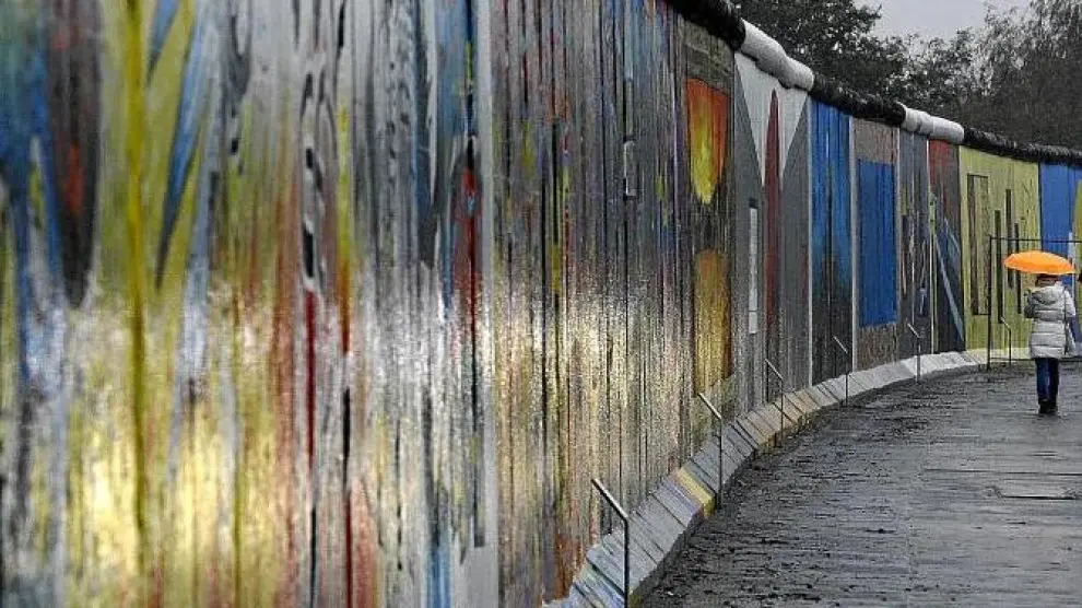 Una mujer pasea junto a un segmento del East Side Gallery de Berlín, el tramo más largo que aún queda en pie del muro.