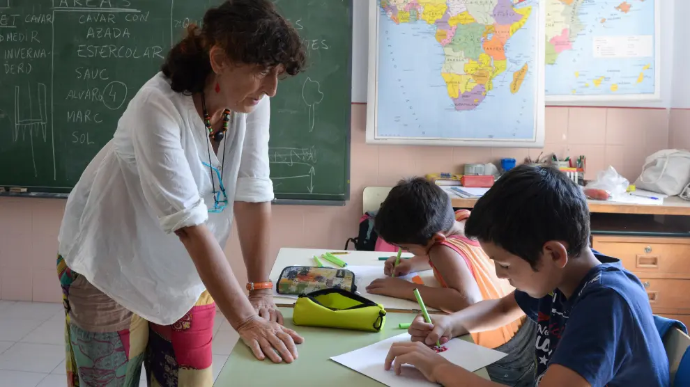 Delfi Ruiz Fernández, maestra de la escuela de Olba, del CRA Javalambre (Teruel), observa el trabajo de dos de sus alumnos