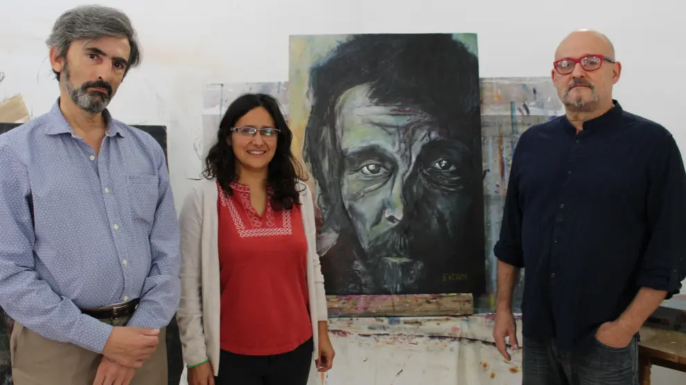 Dos integrantes de Pierres junto al cuadro donado y el artista Fernando Escribano a la derecha.