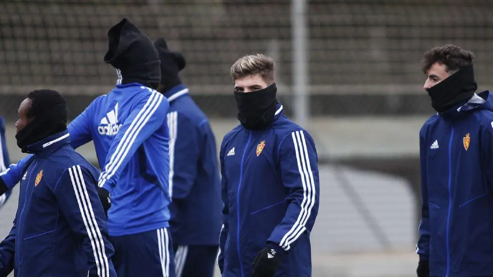 Igbekeme, Guti y Francés, acompañados por otros 'anónimos' compañeros protegidos del intenso frío en el entrenamiento matinal del Real Zaragoza en la Ciudad Deportiva.