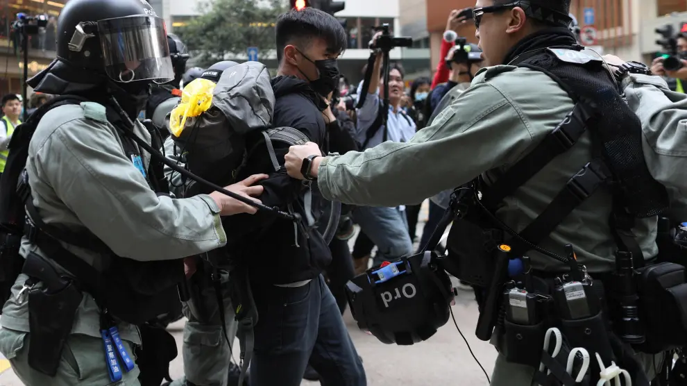 Dos policías retienen a uno de los manifestantes este domingo en las calles de Hong Kong.