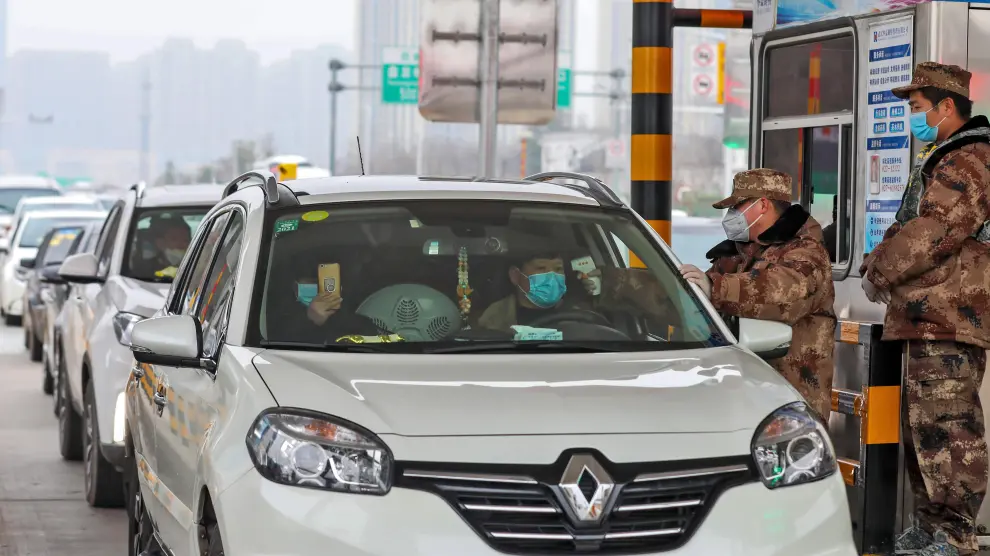 Un militar comprueba la temperatura de dos personas en un coche en Wuhan.