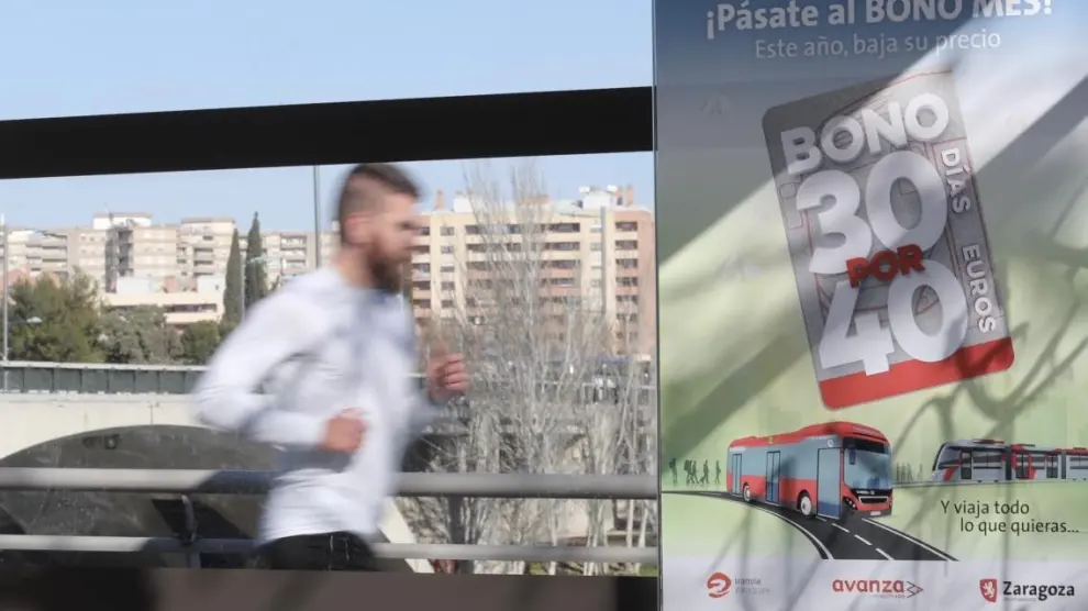 Un hombre pasa corriendo por delante de una marquesina de bus con el anuncio de 30x40.