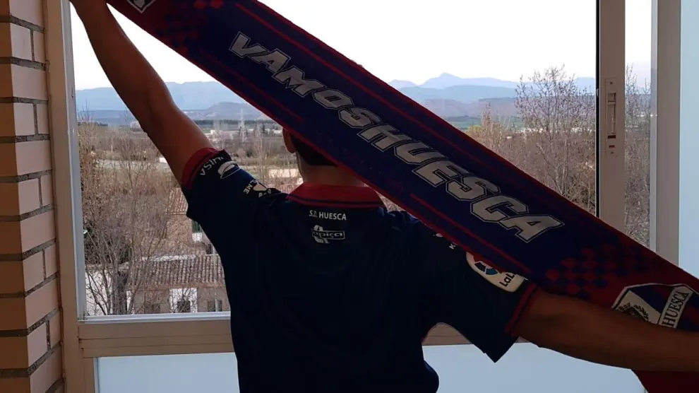Un aficionado de la SD Huesca se asoma a su ventana para cantar el himno.