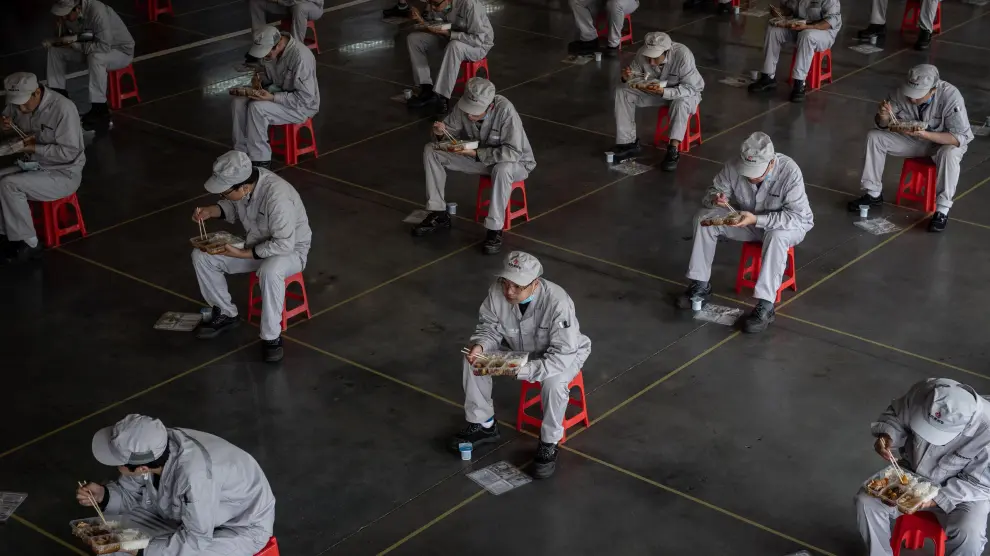 Trabajadores chinos comen en asientos habilitados y colocados para mantener la distancia prudencial recomendada en la fábrica Dongfeng Honda en Wuhan.