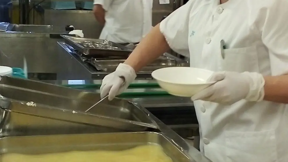 Una de las trabajadoras de la cocina del Servet sirve una ración en un plato.