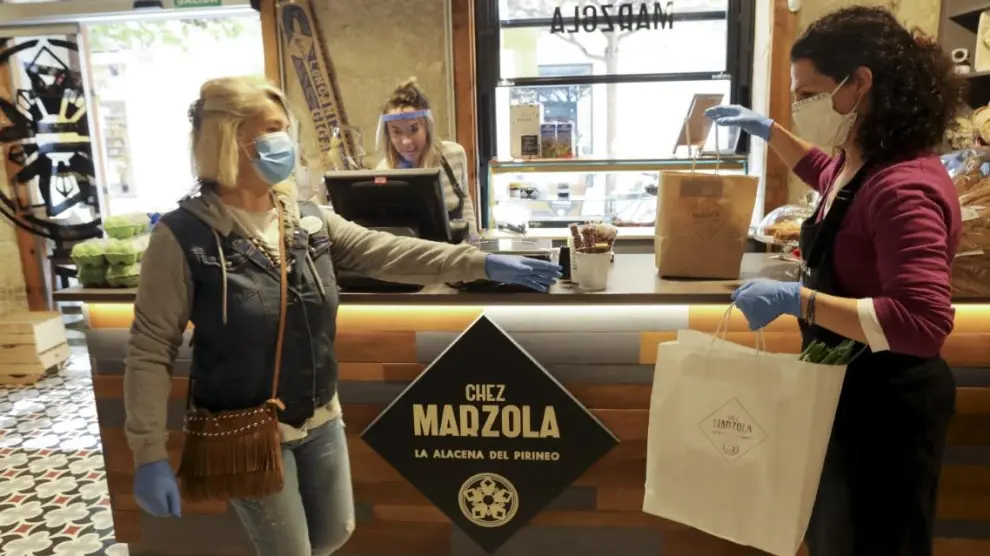 Una voluntaria de la AECC recoge un pedido a domicilio en la tienda de Chez Marzola, de Elena Bernad.