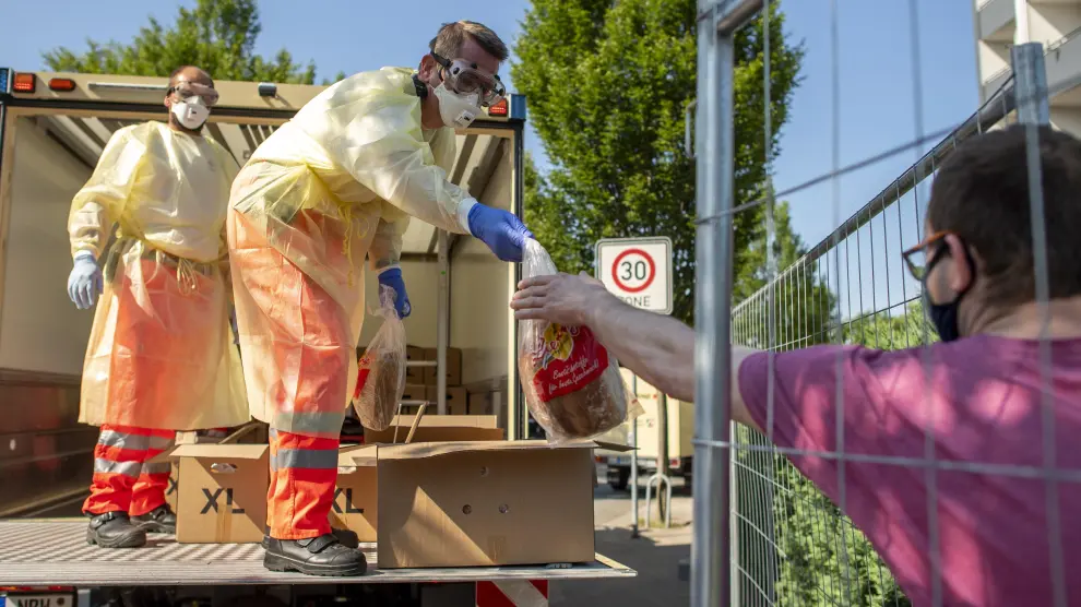 Voluntarios de Cruz Roja entregan pan en una de las casas de los trabajadores del grupo cárnico Toennies puestas en cuarentena por el brote de coronavirus en la planta de Renania.
