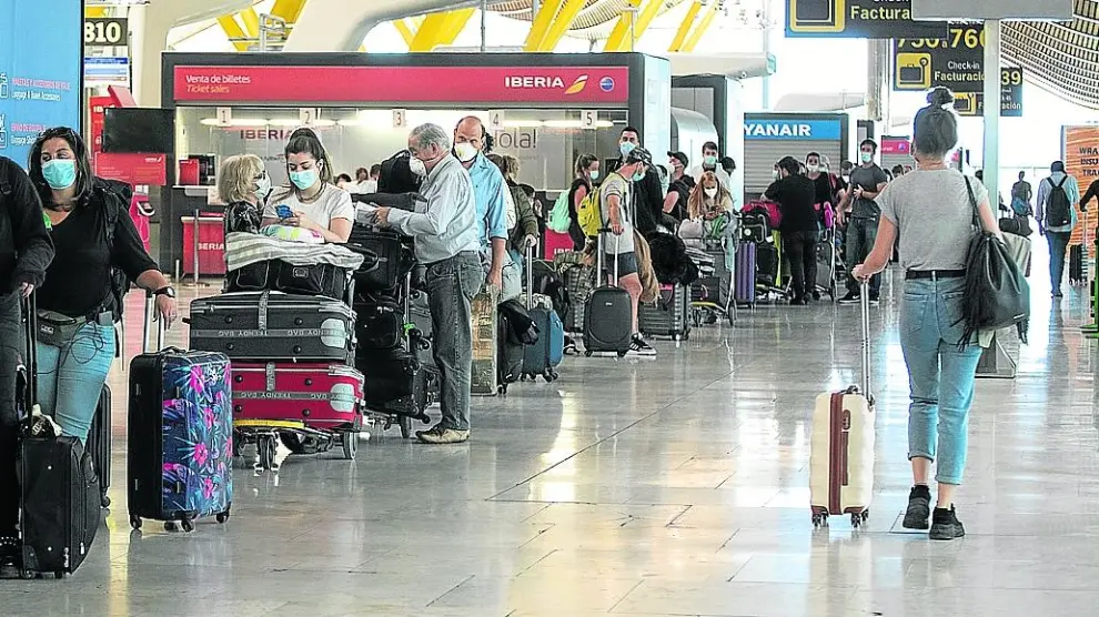 Viajeros esperando para facturar sus maletas en el aeropuerto de Barajas, en Madrid.