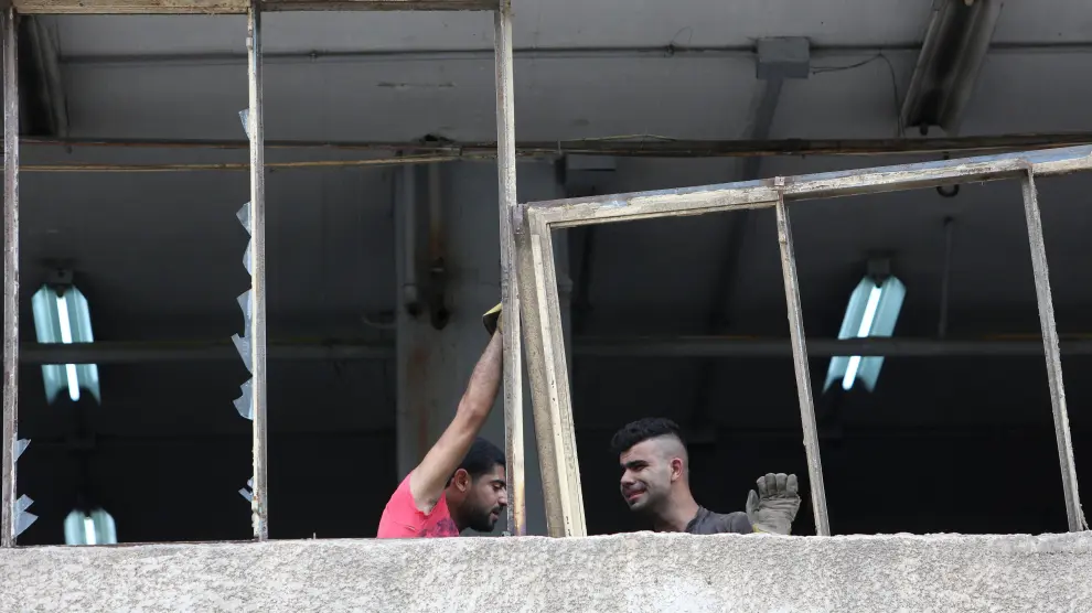 Dos hombres trabajan para reparar uno de los edificios afectados por la explosión este jueves en Beirut.